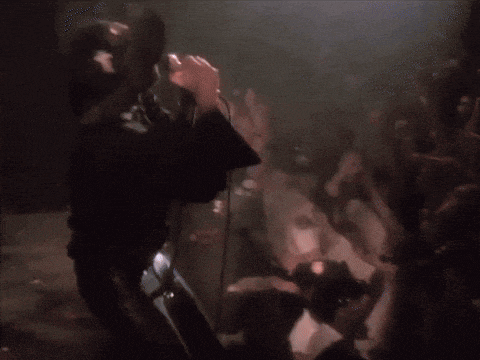 a man is singing into a microphone in front of a crowd of people