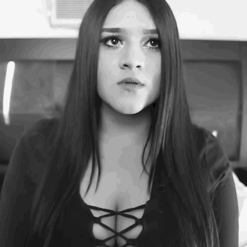 a black and white photo of a woman with long hair and a lace up top