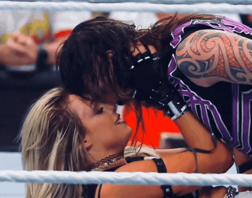 a man with a tattoo on his arm kisses a woman in a ring