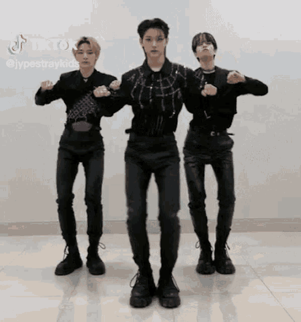 three men are standing next to each other on a tiled floor and dancing .