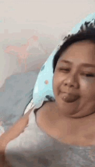 a woman is laying in bed with her tongue out .