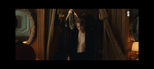 a man in a suit is standing in front of a mirror with the letter s on the bottom