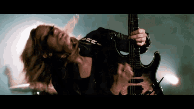 a woman is playing a guitar with the letter e on her chest