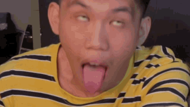 a man in a yellow striped shirt is sticking out his tongue .