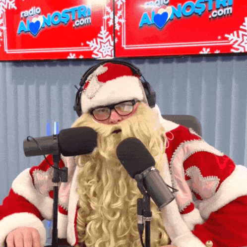 a man dressed as santa claus is sitting in front of a microphone in front of a sign that says radio alonsostri.com