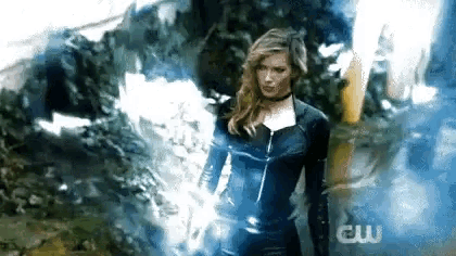 a woman in a superhero costume is standing in front of a smokey background .