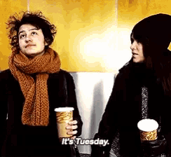 a woman holding a cup that says it 's tuesday next to another woman