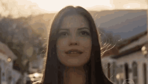 a woman with long hair is standing in front of a building and smiling .