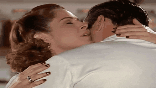 a woman is kissing a man on the cheek while wearing a ring
