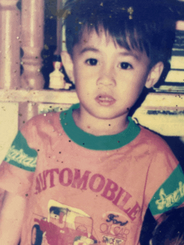a young boy is wearing a shirt that says automobile on it
