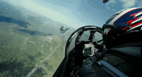 a fighter jet is flying over a forest with a pilot in the cockpit