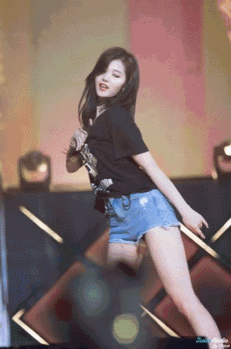 a woman in a black shirt and shorts is dancing on stage
