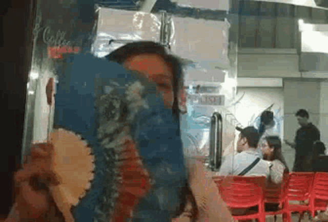 a woman is covering her face with a fan in front of a sign that says coffee