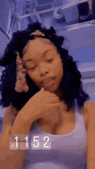 a woman with curly hair and a headband is taking a selfie in a bathroom with her eyes closed .