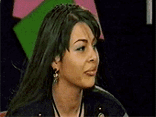 a close up of a woman 's face wearing earrings and a black jacket