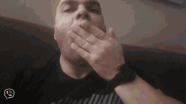a man covering his mouth with his hand while wearing a wristwatch