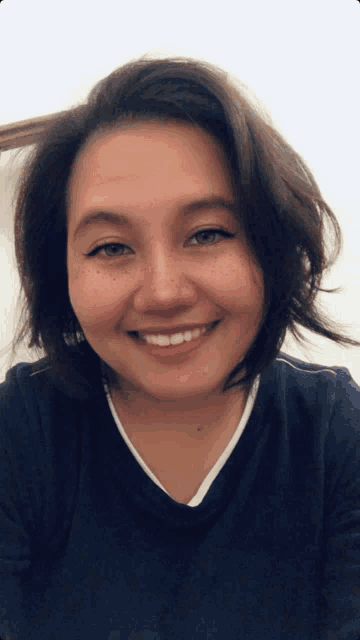 a woman with freckles on her face is smiling and wearing a blue shirt