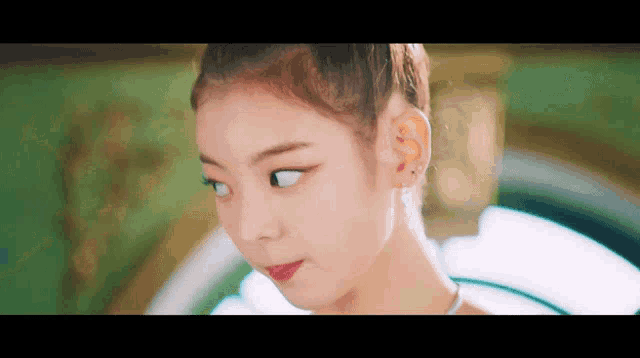 a close up of a girl 's face with white eyes and a bun .