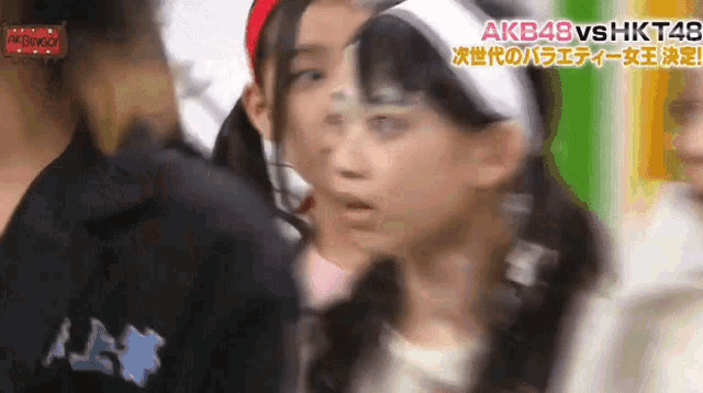 a group of girls are standing next to each other with a sign that says akb48 vs hkt48 on it