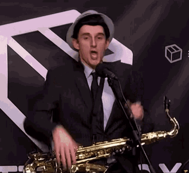 a man in a suit and tie is playing a saxophone in front of a microphone