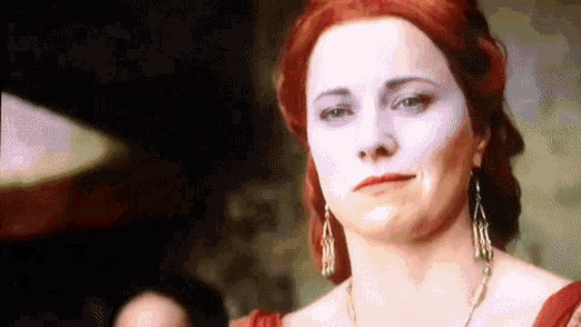 a woman with red hair and white face paint