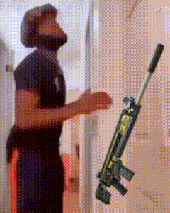 a man in a helmet is standing next to a gun in a room .