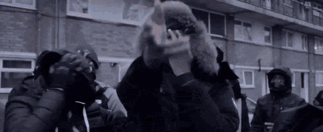 a group of people are standing in front of a building and a man is holding a gun .