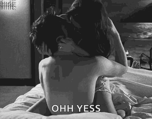 a man and woman are kissing on a bed .