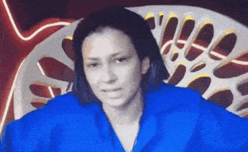 a woman in a blue shirt is sitting in front of a white chair