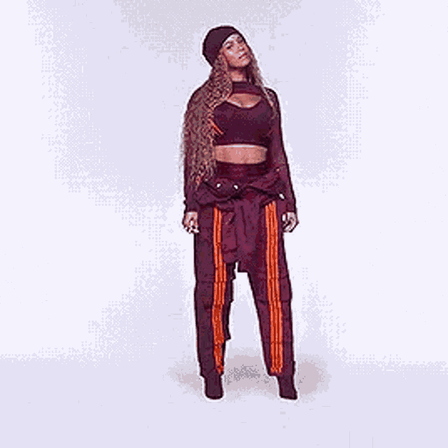 a woman in a crop top and cargo pants is standing on a white background .