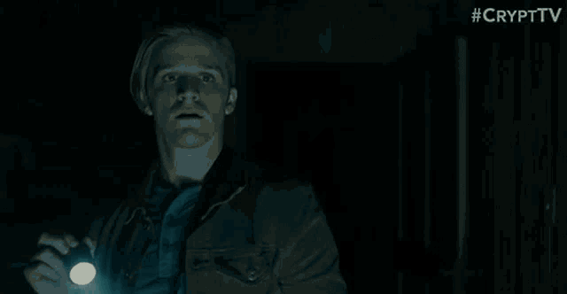 a man is standing in a dark room holding a flashlight .