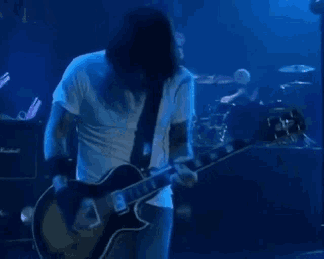 a man in a white shirt is playing a guitar on a stage .