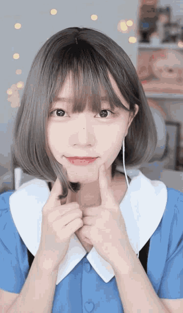 a girl with short grey hair and bangs wearing a blue dress