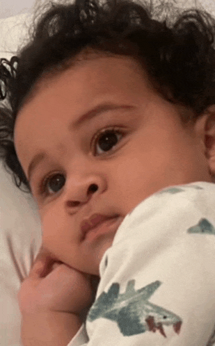a baby is laying on a bed and looking at the camera .