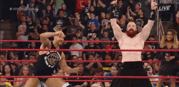 a man in a wrestling ring with his arms in the air and a crowd behind him