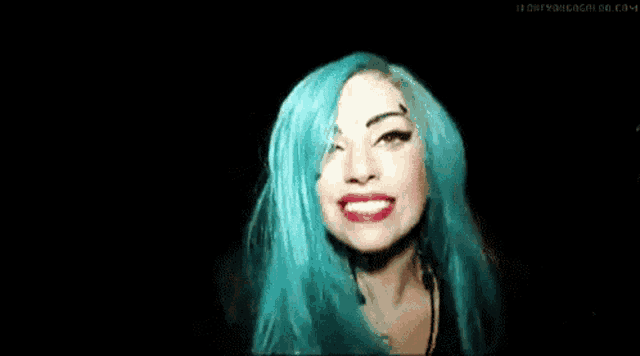 a woman with blue hair is blowing a kiss with red lips .