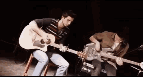 two men are playing guitars on a stage with a laney amplifier in the background .
