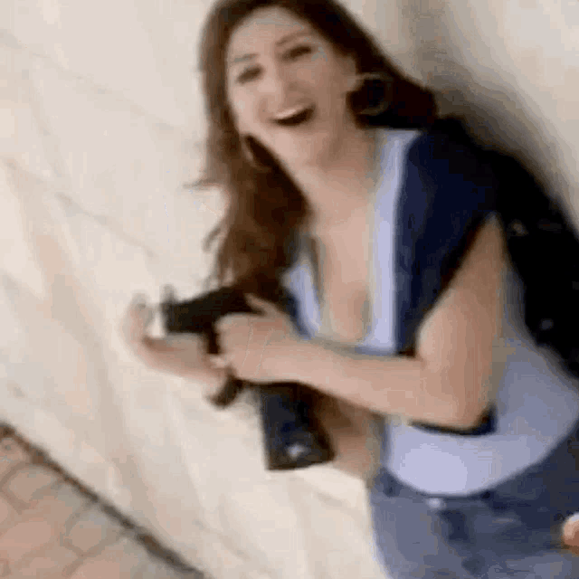 a woman is holding a gun and smiling while sitting on the ground .