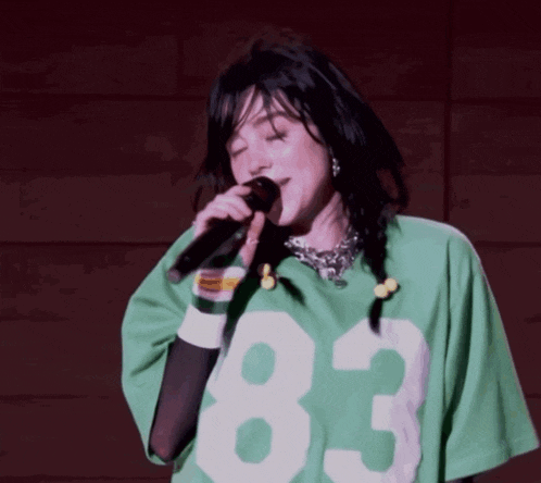 a woman singing into a microphone wearing a green 83 jersey
