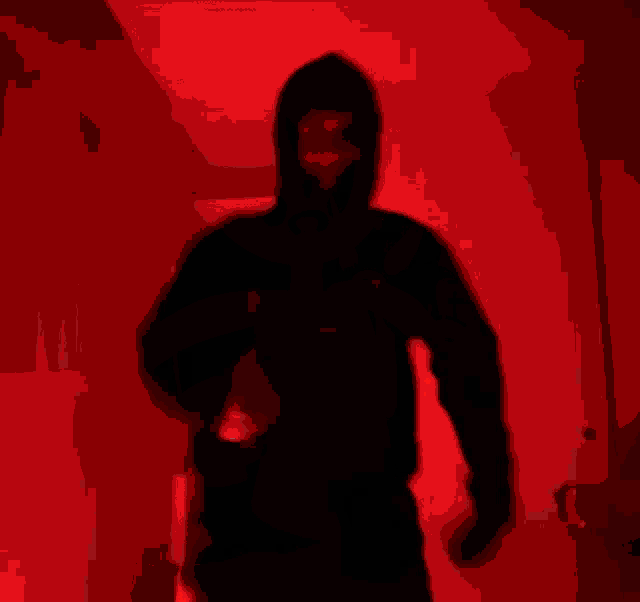 a blurry picture of a man in a hoodie dancing in a red room .