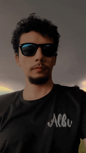 a man wearing sunglasses and a black shirt that says albe