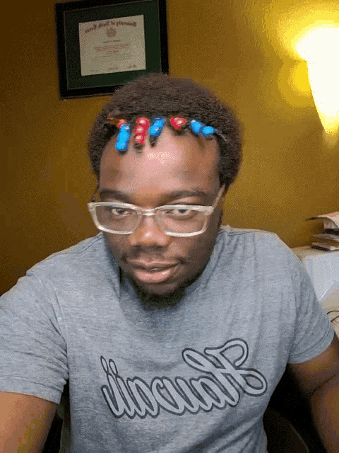 a man wearing glasses and a grey shirt that says inclusive