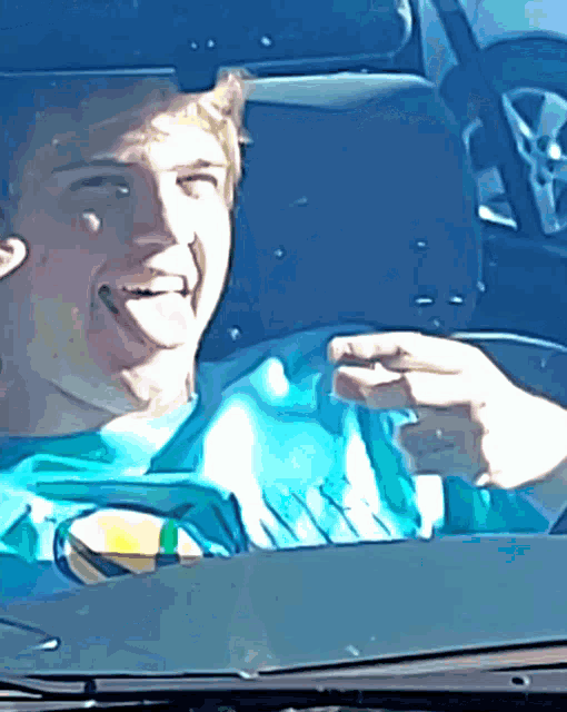 a man in a blue shirt is sitting in a car