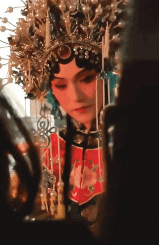 a woman wearing a crown and a red dress looks at herself in a mirror