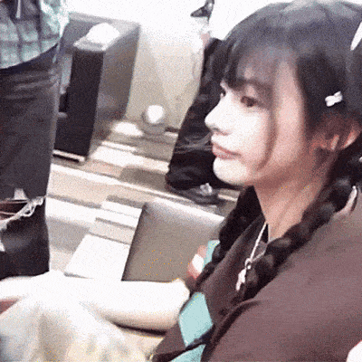 a girl with braids is sitting in a chair and looking at the camera