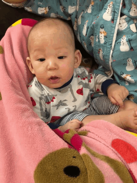 a baby is laying on a pink blanket with a snowman on it