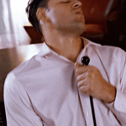 a man is singing into a microphone while wearing a white shirt
