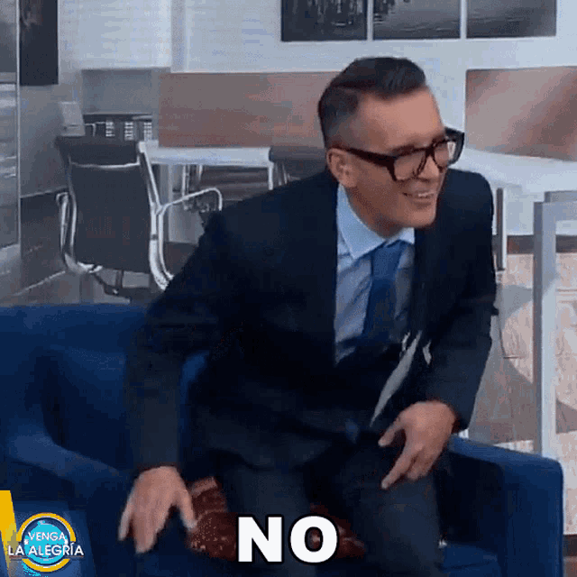 a man in a suit and tie is sitting on a couch with the word no written on the bottom