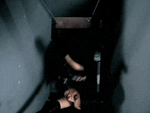 a woman is laying down in a dark room with a knife in her hand .