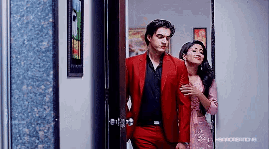 a man in a red suit is walking next to a woman in a pink dress .